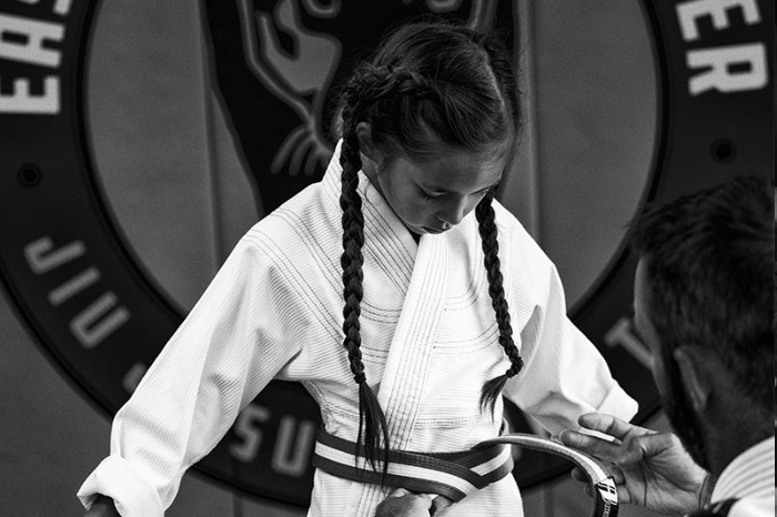 An image of a girl getting her new Brazilian Jiu Jitsu belt.